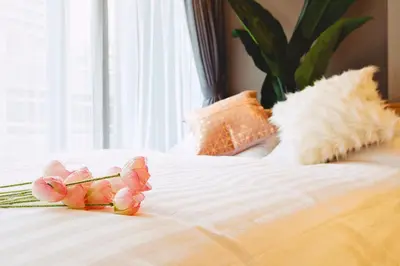 a white bed with pink flowers on top of it at 都心罕见东京奢华设计师Keob带榻榻米 戴森&POLA顶级配置4分钟到东京站 20分钟到迪士尼 最大3人 in Tokyo