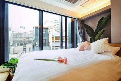 a bedroom with a large white bed with a large window at 都心罕见东京奢华设计师Kdob带榻榻米 戴森&POLA顶级配置4分钟到东京站 20分钟到迪士尼 最大3人 in Tokyo