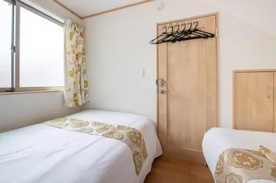 a small bedroom with two beds and a window at THE VILLA TAKADANOBABA in Tokyo