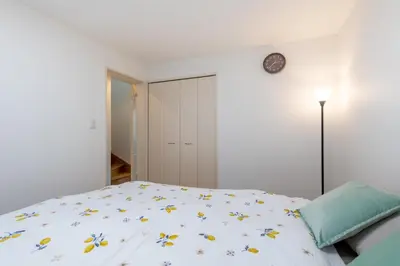 a white bedroom with a bed and a clock on the wall at \u65b0\u5bbf6\u4e01\u76ee\u6238\u5efa in Tokyo
