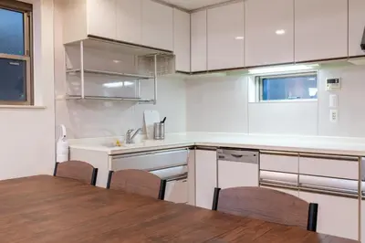 a kitchen with white cabinets and a table and chairs at \u65b0\u5bbf6\u4e01\u76ee\u6238\u5efa in Tokyo