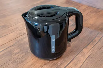 a black mug sitting on top of a wooden table at \u65b0\u5bbf6\u4e01\u76ee\u6238\u5efa in Tokyo