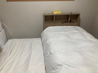 a white bed in a room with a shelf at Sky Tree INN (\u6674\u6a39\u5bbf\uff09stay ASAKUSA in Tokyo