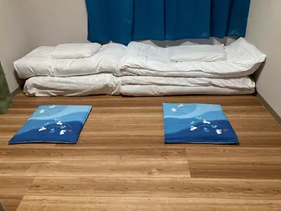 two blue mats on a wooden floor next to a bed at Sky Tree INN (\u6674\u6a39\u5bbf\uff09stay ASAKUSA in Tokyo