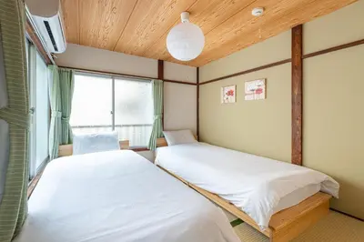 two beds in a room with a window at \u6771\u4e0a\u91ce\u6238\u5efa in Tokyo