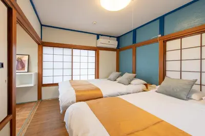two beds in a room with blue walls and windows at \u897f\u65b0\u5bbf5\u4e01\u76ee\u6238\u5efa in Tokyo