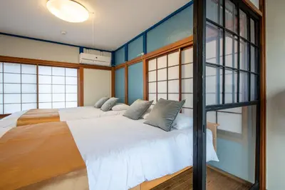 two beds in a room with blue walls and windows at \u897f\u65b0\u5bbf5\u4e01\u76ee\u6238\u5efa in Tokyo