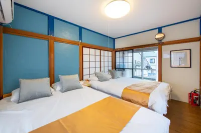 two beds in a room with blue walls and windows at \u897f\u65b0\u5bbf5\u4e01\u76ee\u6238\u5efa in Tokyo