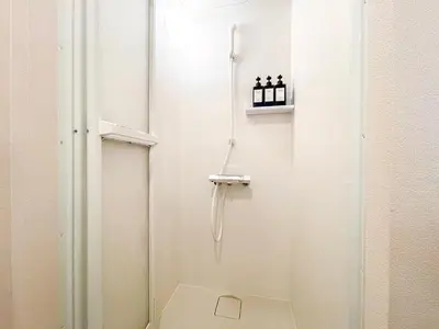 a bathroom with a shower with a white door at Dolce Shibuya in Tokyo