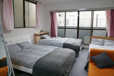 a bedroom with three beds and a window at TokyoGuest Akihabara in Tokyo
