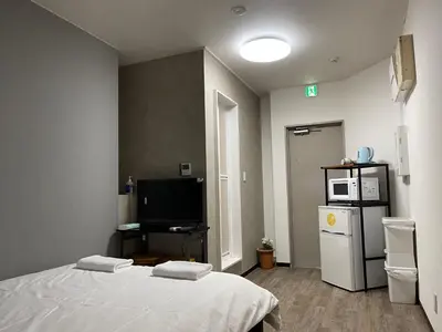 a bedroom with a white bed and a tv at TokyoGuest Akihabara in Tokyo