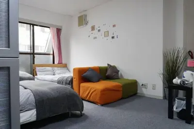 a bedroom with two beds and an orange chair at TokyoGuest Akihabara in Tokyo