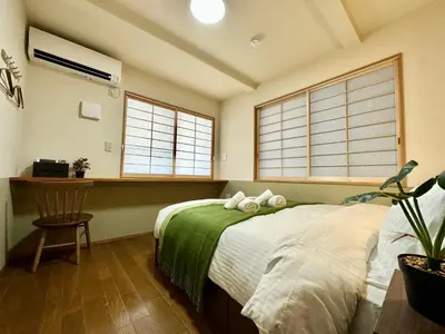 a bedroom with a bed and a table and two windows at N9-luxury guest room in Shinjuku in Tokyo