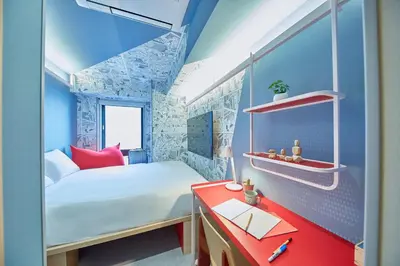 a small room with a bed and a red desk at lyf Ginza Tokyo in Tokyo