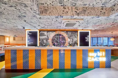 a lobby with a colorful counter with a mural on the wall at lyf Ginza Tokyo in Tokyo
