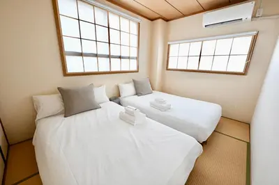 two beds in a small room with two windows at Tatekawa 333 Residence - \u7acb\u5ddd\u4e09\u4e09\u4f4f\u5b85- crib free in Tokyo