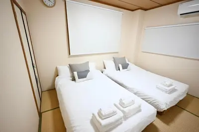 two beds in a small room with white sheets at Tatekawa 333 Residence - \u7acb\u5ddd\u4e09\u4e09\u4f4f\u5b85- crib free in Tokyo