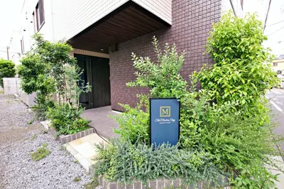 a sign in front of a building with plants at The Masters Stay SETAGAYA KYODO in Tokyo