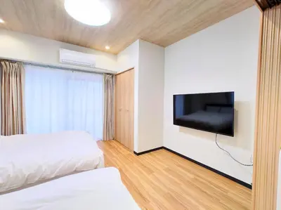 a hotel room with two beds and a flat screen tv at Mezon Akihabara Guest House in Tokyo
