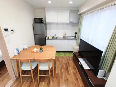 a small kitchen with a table and chairs in a room at Mezon Akihabara Guest House in Tokyo