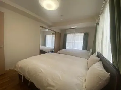 a bedroom with two white beds and a mirror at Mezon Akihabara Guest House in Tokyo
