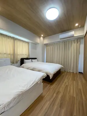 two beds in a room with wooden floors at Mezon Akihabara Guest House in Tokyo