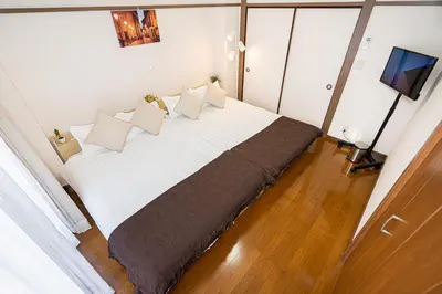 a bedroom with a large white bed with pillows at \u62bc\u4e0a\u99c5\u304b\u3089\u5f92\u6b655\u5206 \u7121\u6599WiFi \u30b9\u30ab\u30a4\u30c4\u30ea\u304c\u773a\u671b\u3067\u304d\u307e\u3059 \u6700\u59276\u4ebaOK in Tokyo