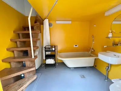 a bathroom with yellow walls and a tub and a sink at 1 stop to Shinjuku! Central NAKANO! up to 3ppl.cozy bright room. in Tokyo