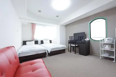 a bedroom with two beds and a red couch at Hirojo Building 203,303,403,603,703 - Vacation STAY 15454 in Tokyo