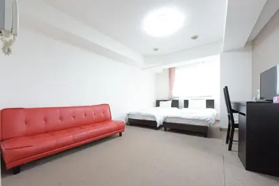 a living room with a red couch and a bed at Hirojo Building 203,303,403,603,703 - Vacation STAY 15454 in Tokyo