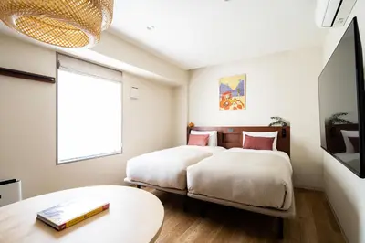 two beds in a room with a table and a window at Section L Ueno-Hirokoji in Tokyo