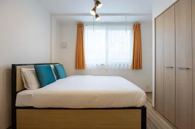 a bedroom with a bed with blue pillows and a window at \u30a6\u30a7\u30eb\u30b9\u30af\u30a8\u30a2\u30a4\u30ba\u30e0\u5927\u585a in Tokyo
