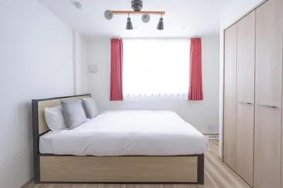 a bedroom with a bed with a window and red curtains at \u30a6\u30a7\u30eb\u30b9\u30af\u30a8\u30a2\u30a4\u30ba\u30e0\u5927\u585a in Tokyo