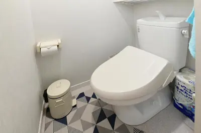 a bathroom with a white toilet and a trash can at JH Yellow Guest House in Tokyo