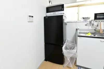 a black refrigerator with a microwave above it in a kitchen at JH Yellow Guest House in Tokyo