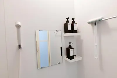 a bathroom mirror with two bottles on a wall at JH Yellow Guest House in Tokyo