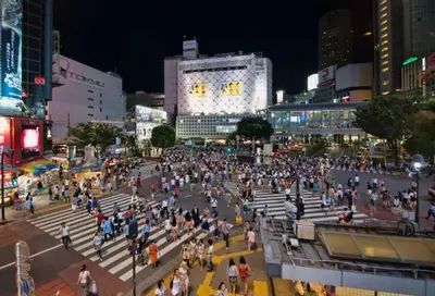 a crowd of people walking around a street at night at PDO inn Sangenjaya Art residence in Tokyo