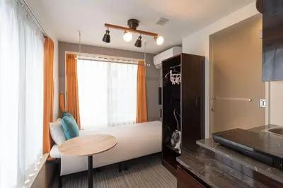 a room with a bed and a table and a window at HJ PLACE SHIBUYA in Tokyo