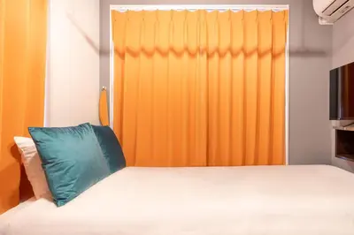 a bed with a blue pillow in front of a window at HJ PLACE SHIBUYA in Tokyo