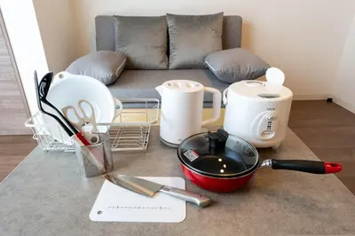a kitchen counter with utensils on a table with a couch at JASPER Waseda in Tokyo