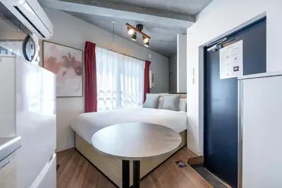 a small room with a bed and a table at JASPER Waseda in Tokyo