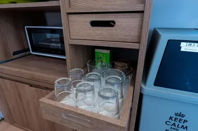 a wooden drawer with glasses in front of a microwave at Beige in Tokyo