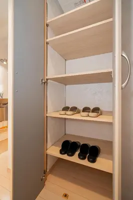 a closet with wooden shelves with shoes on them at ZAITO Tokyo Narihira Hotel\u3000\u62bc\u4e0a\u99c5\u304b\u3089\u5f92\u6b69\u516b\u5206\u30db\u30c6\u30eb in Tokyo