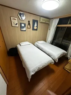 two beds in a room with pictures on the wall at Yama house AD0234 in Tokyo