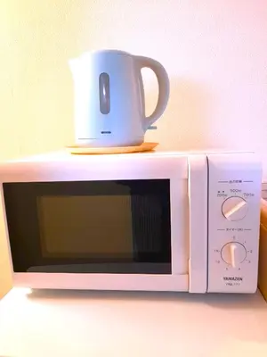 a white microwave with a cup on top of it at Shinjuku Harusame Apartment -Twin room- in Tokyo