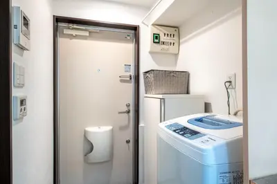a bathroom with a washer and dryer next to a door at \u30f4\u30a3\u30f3\u30c6\u30fc\u30b8\u30c7\u30b6\u30a4\u30f3\u795e\u697d\u5742102 in Tokyo