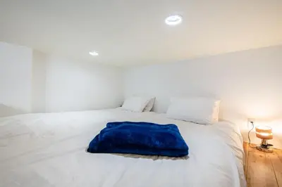 a white bed with a blue pillow on it at \u30f4\u30a3\u30f3\u30c6\u30fc\u30b8\u30c7\u30b6\u30a4\u30f3\u795e\u697d\u5742102 in Tokyo