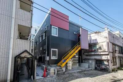 a black building with a yellow staircase on the side at \u30f4\u30a3\u30f3\u30c6\u30fc\u30b8\u30c7\u30b6\u30a4\u30f3\u795e\u697d\u5742102 in Tokyo