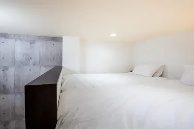 a bedroom with a white bed and a concrete wall at \u30f4\u30a3\u30f3\u30c6\u30fc\u30b8\u30c7\u30b6\u30a4\u30f3\u795e\u697d\u5742102 in Tokyo