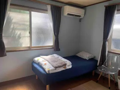 a small bedroom with a blue bed and a window at M&Ks house in Tokyo